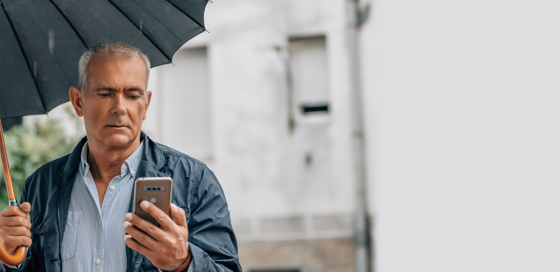 Man in the rain checking is phone