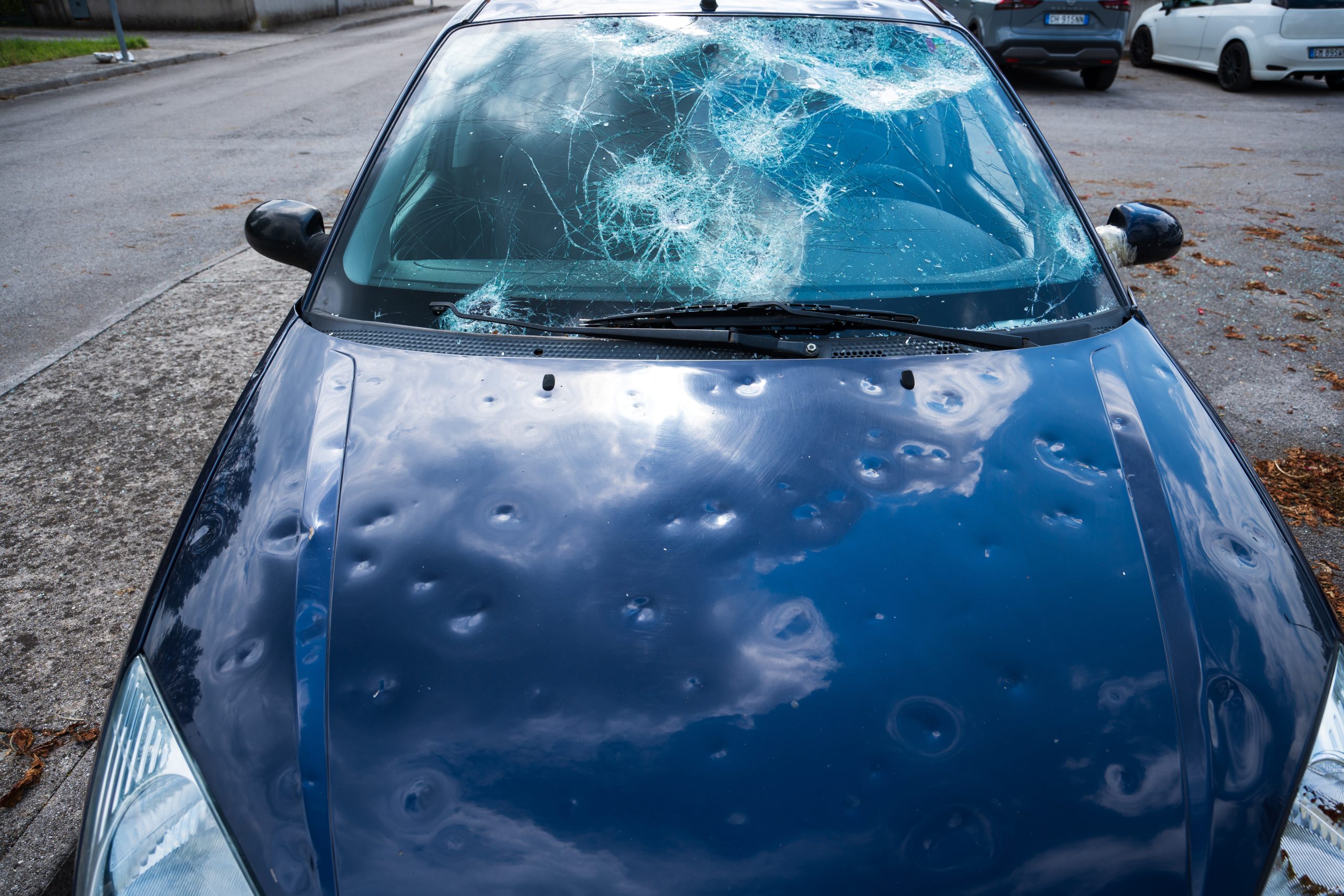 hail damage to car. damaged hood and windshield